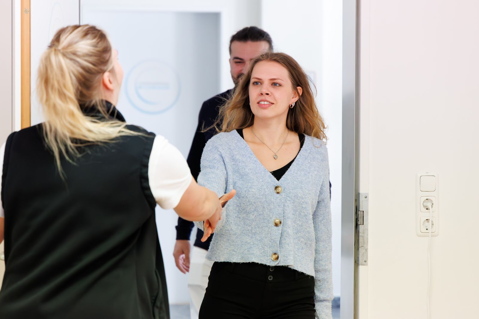 Kollegin begrüßt eine neue Mitarbeiterin per Handschlag im Flur des Therapiezentrums